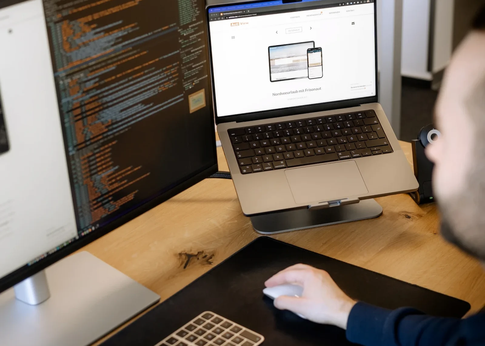 Webentwickler beim Code-Debugging auf Laptop und großem Bildschirm